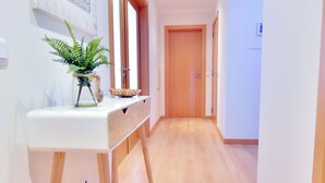 A hallway with a wooden floor, a white desk with a plant, and a wooden door at the end. - FLORIPES LUXURY APARTMENT WITH POOL ON ROOFTOP (Olhão)