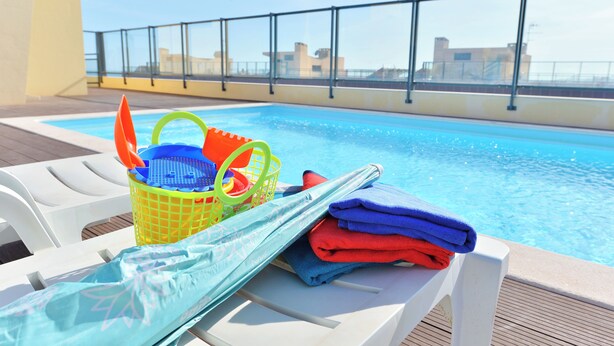 A poolside area with lounge chairs, a pool, and a view of buildings in the background. - FLORIPES LUXURY APARTMENT WITH POOL ON ROOFTOP (Olhão)