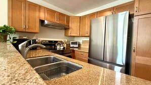 A modern kitchen with granite countertops, stainless steel appliances, and wooden cabinets. - Beachy Malibu Loft - Pool / Tennis / Gym (Malibu)