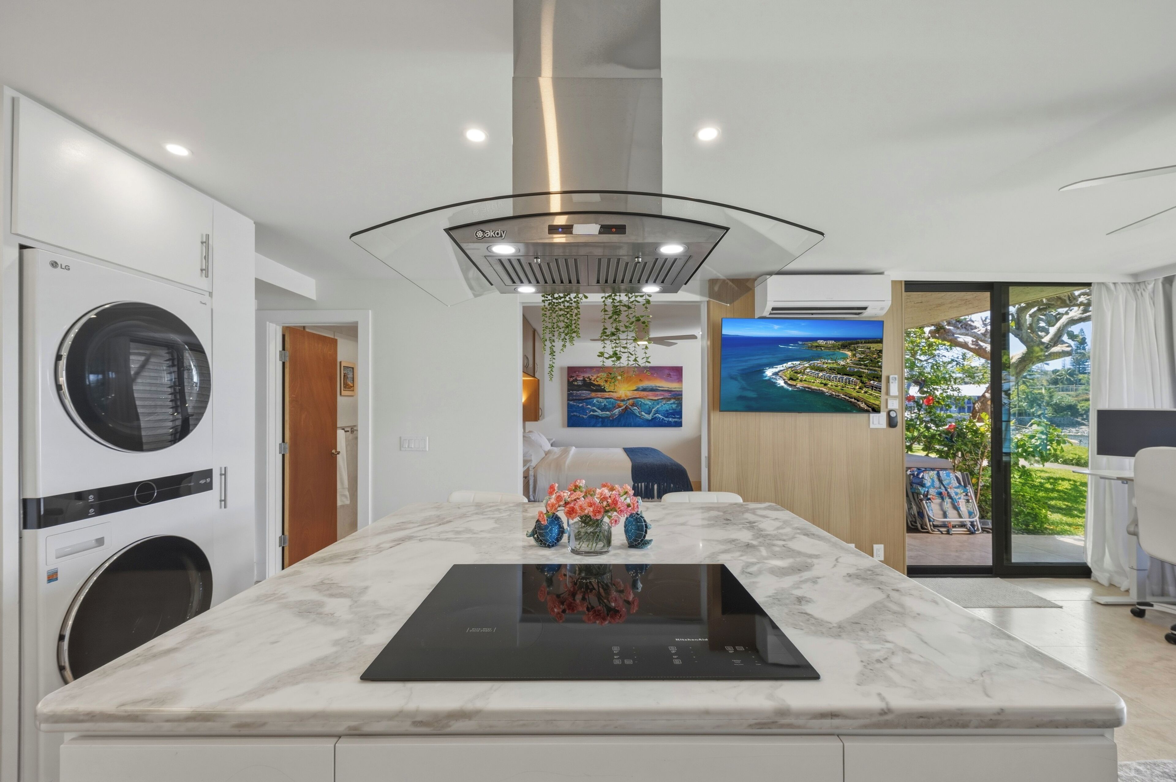 A modern kitchen with a built-in stove, a washing machine, and a large window with a view.