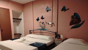 Een kamer met twee bedden, een kledingkast, een wandplank en een decoratief schilderij van een vlinder.