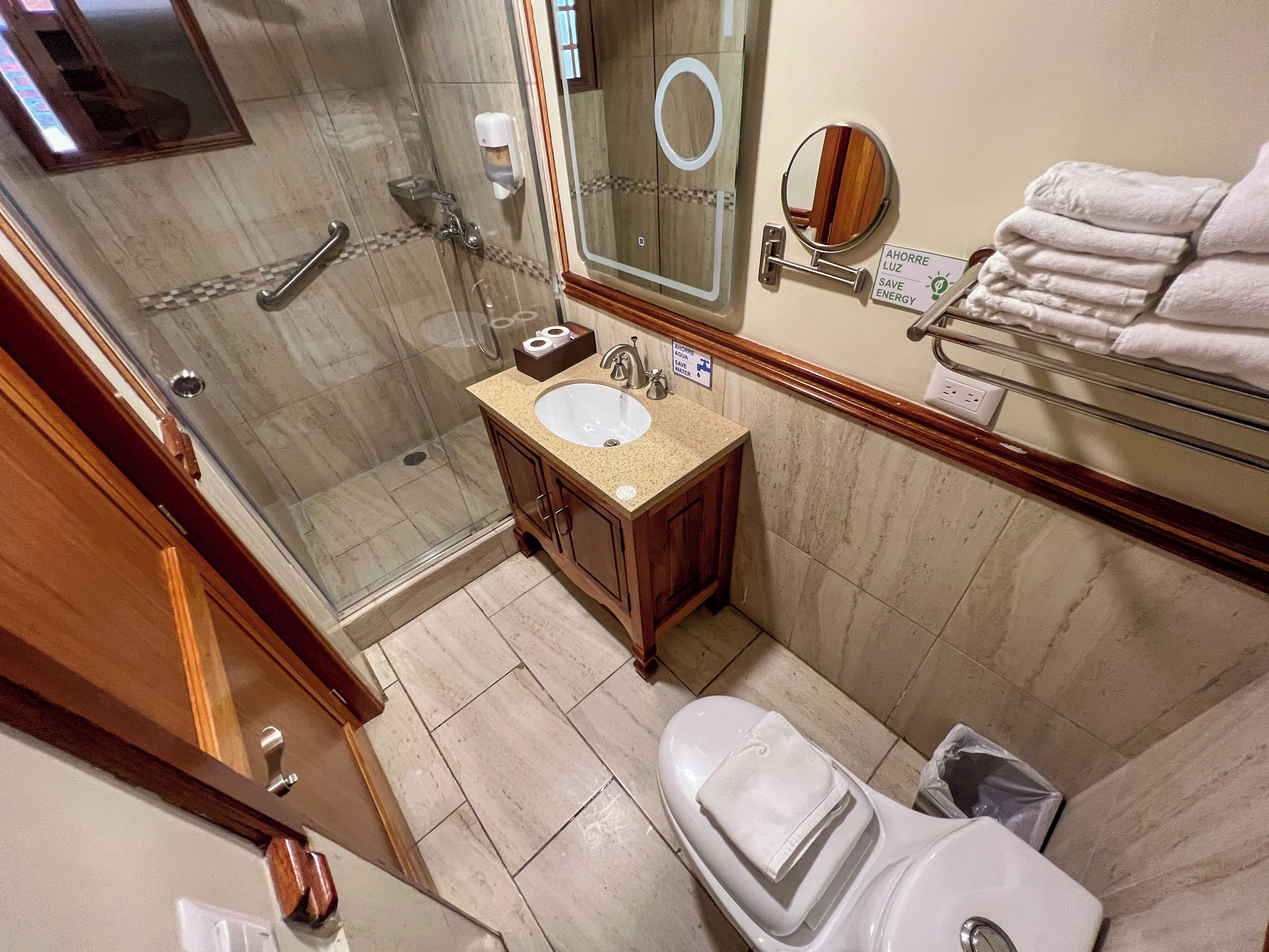 A bathroom with a glass shower, a sink, a toilet, and a towel rack.