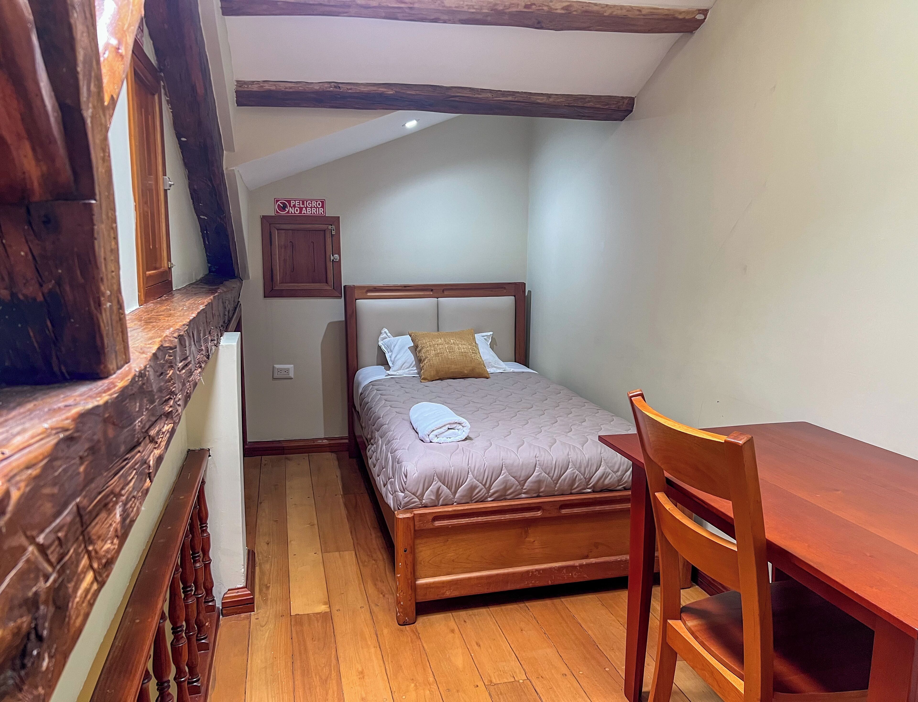 Una camera da letto con un letto, una sedia, un tavolo e una trave in legno.