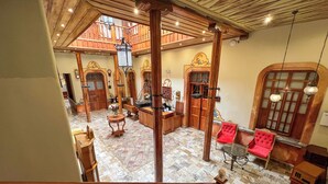 A spacious lobby with a high ceiling, wooden columns, and a checkered floor. - Hotel Boutique Magdalena By Chat Noir (Cuenca)