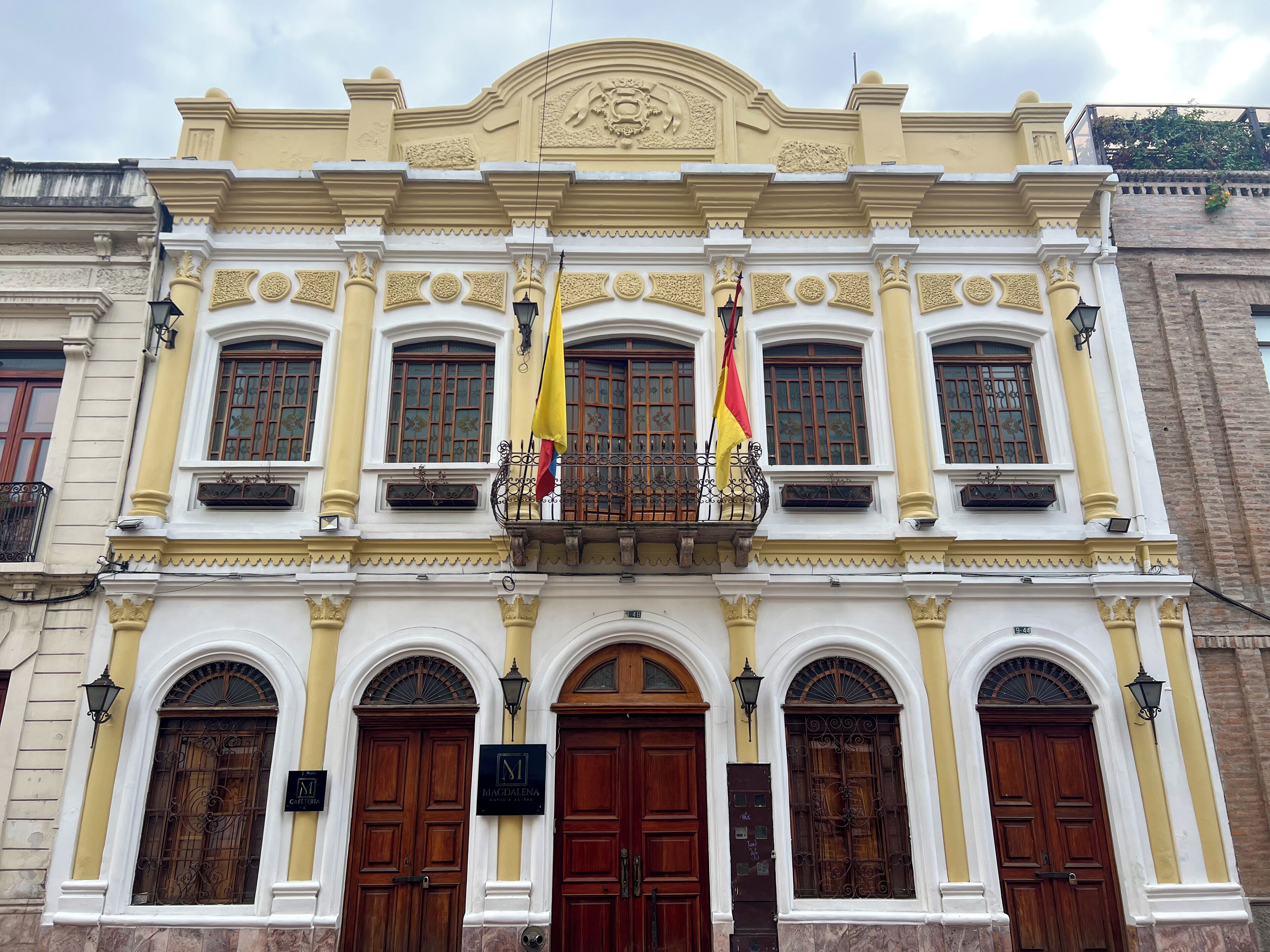 A building with a symmetrical facade, featuring a central balcony with a wrought iron railing, and multiple arched windows with decorative iron grilles.