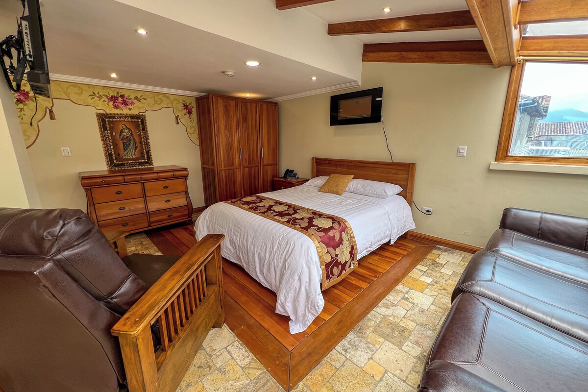 Un dormitorio con una cama de madera, un armario de madera, un televisor y una ventana con vistas.