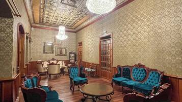 A room with ornate ceiling, chandeliers, and vintage furniture.