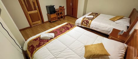 Une chambre d’hôtel avec deux lits, une télévision, un bureau avec un ordinateur et une armoire.