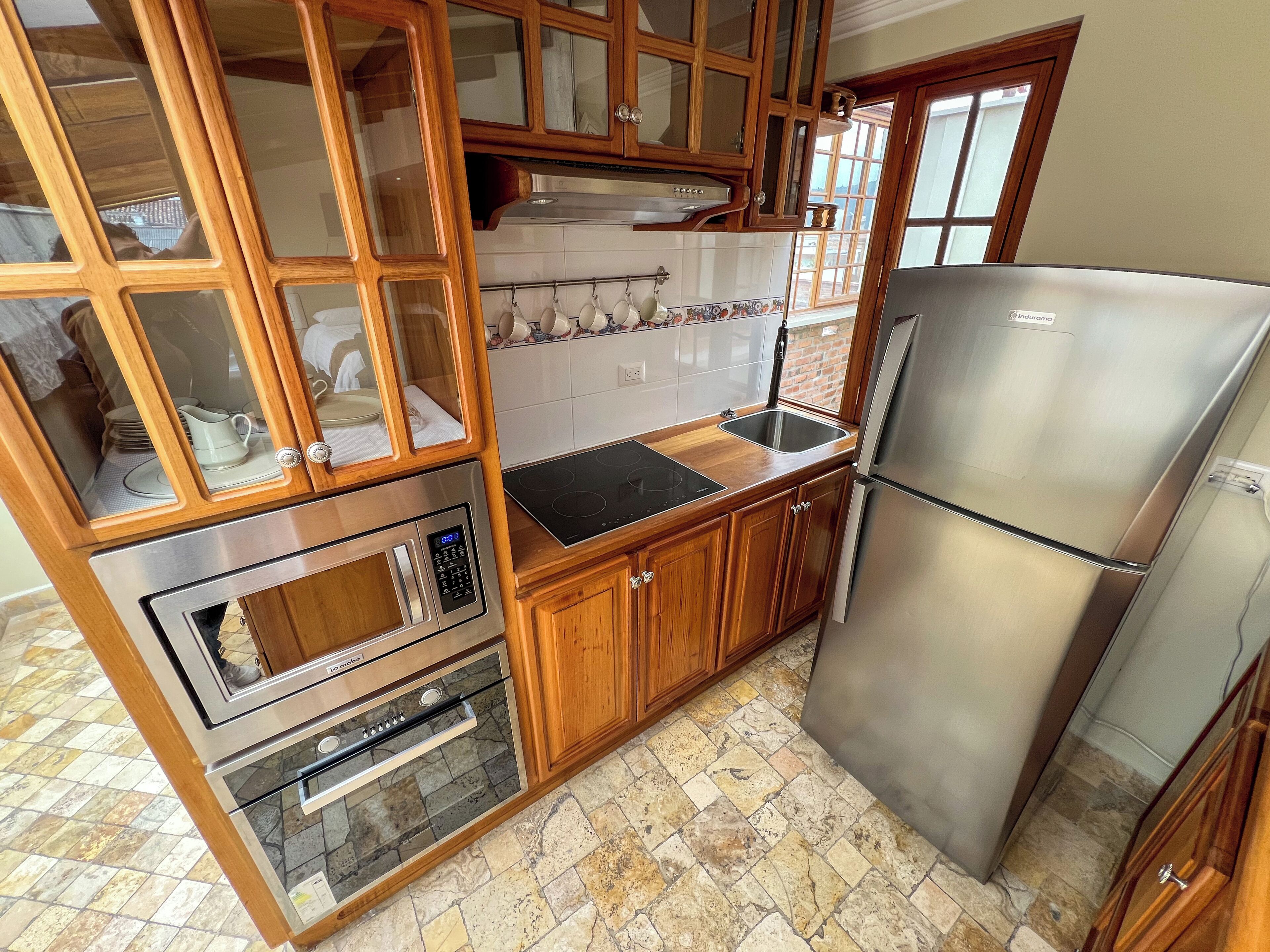 A kitchen with wooden cabinets, a stainless steel refrigerator, an oven, and a sink.