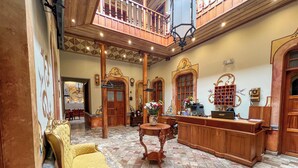 A spacious lobby with a high ceiling, wooden furniture, and a tiled floor. - Hotel Boutique Magdalena By Chat Noir (Cuenca)