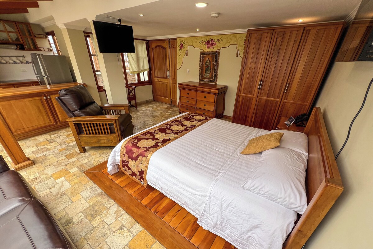 Un dormitorio con una cama grande, muebles de madera, un televisor y una zona de cocina.