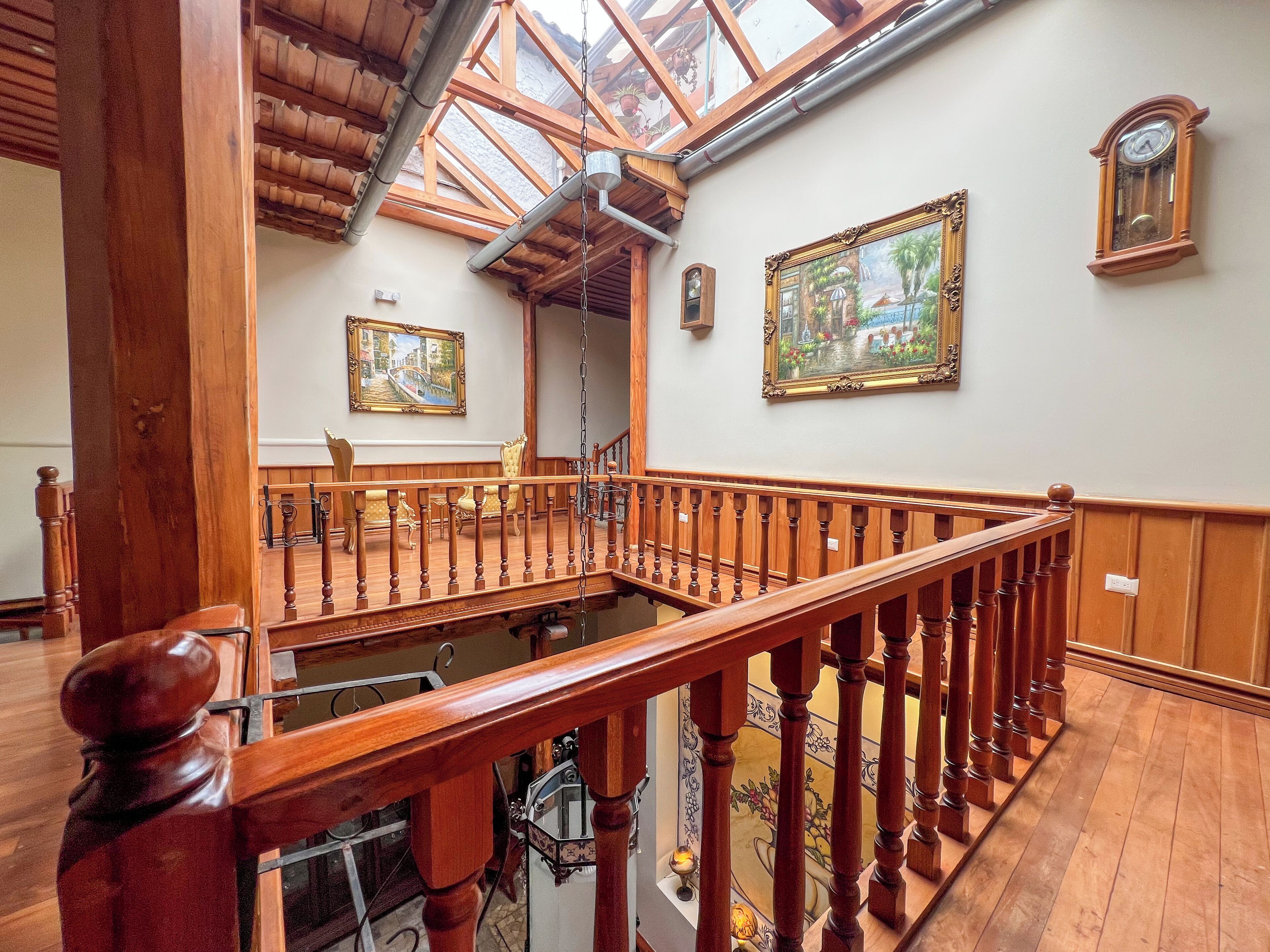 Un escalier en bois avec un plafond en verre, des rampes en bois et un tableau accroché au mur.