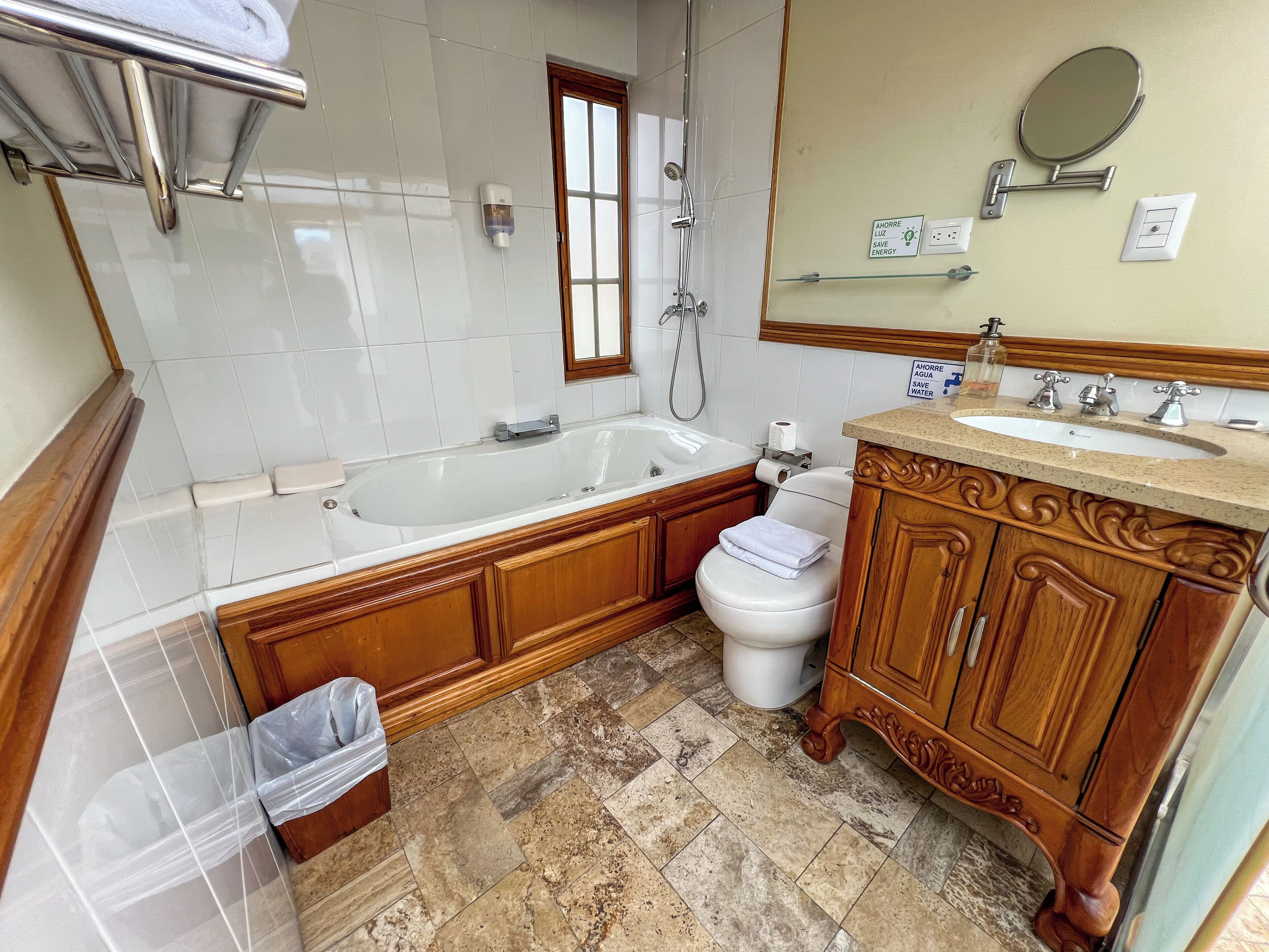 Et badeværelse med badekar, toilet, håndvask og træskabe.