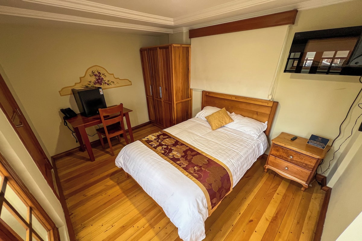 A bedroom with a wooden bed, a desk, and a chair.
