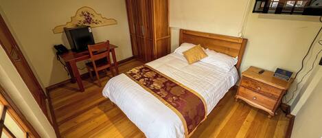 A bedroom with a wooden bed, a desk, and a chair.