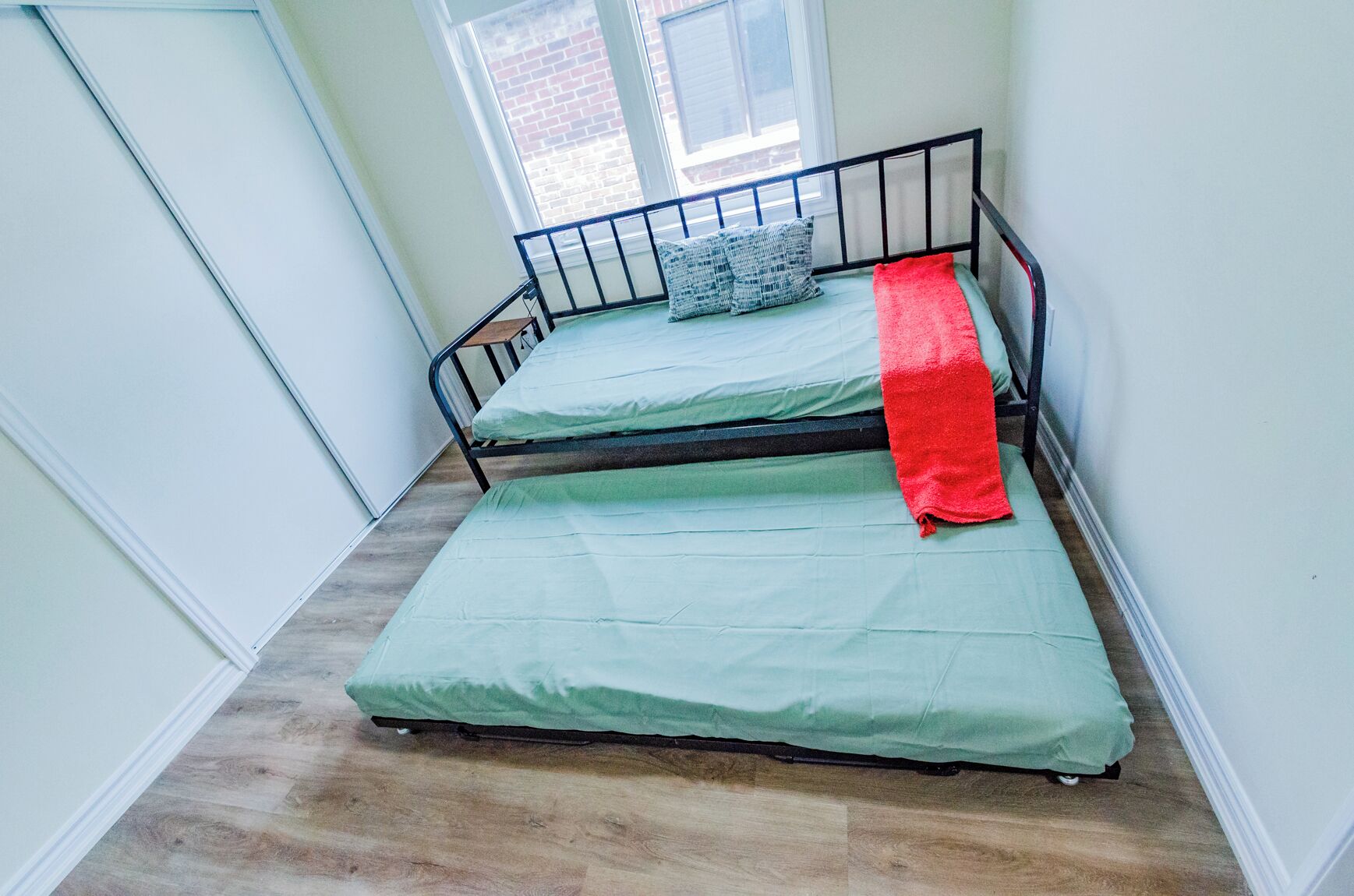 A small, narrow room with a single bed and a window.