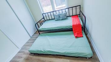 A small, narrow room with a single bed and a window.