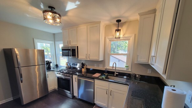 A modern kitchen with stainless steel appliances, white cabinets, and a patterned rug. - Spacious 5-bedroom house in terrific Hopkins with open living and dining space. (Hopkins)