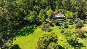 A large house surrounded by lush greenery and a well-maintained lawn. - Wombat Wallows - Kangaroo Valley (Kangaroo Valley)