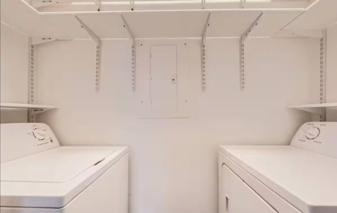 A laundry room with two white washing machines and a door in the center.