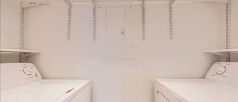 A laundry room with two white washing machines and a door in the center.