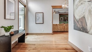 Un couloir doté d’un plancher en bois, d’un banc, d’œuvres d’art encadrées et d’un grand tableau abstrait.