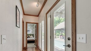 Un couloir doté d’un plancher en bois, d’un luminaire au plafond, d’une porte donnant sur l’extérieur et d’un interrupteur fixé au mur.