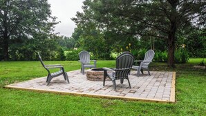 Un espace extérieur aménagé avec quatre fauteuils Adirondack et un foyer.