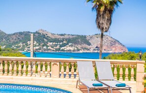 A poolside area with lounge chairs and a view of the sea and mountains. - Nice home in Capdepera with WiFi (Capdepera)
