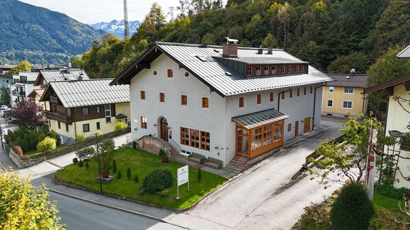 Ein zweistöckiges Gebäude mit geneigtem Dach, großen Fenstern und einer kleinen Veranda.