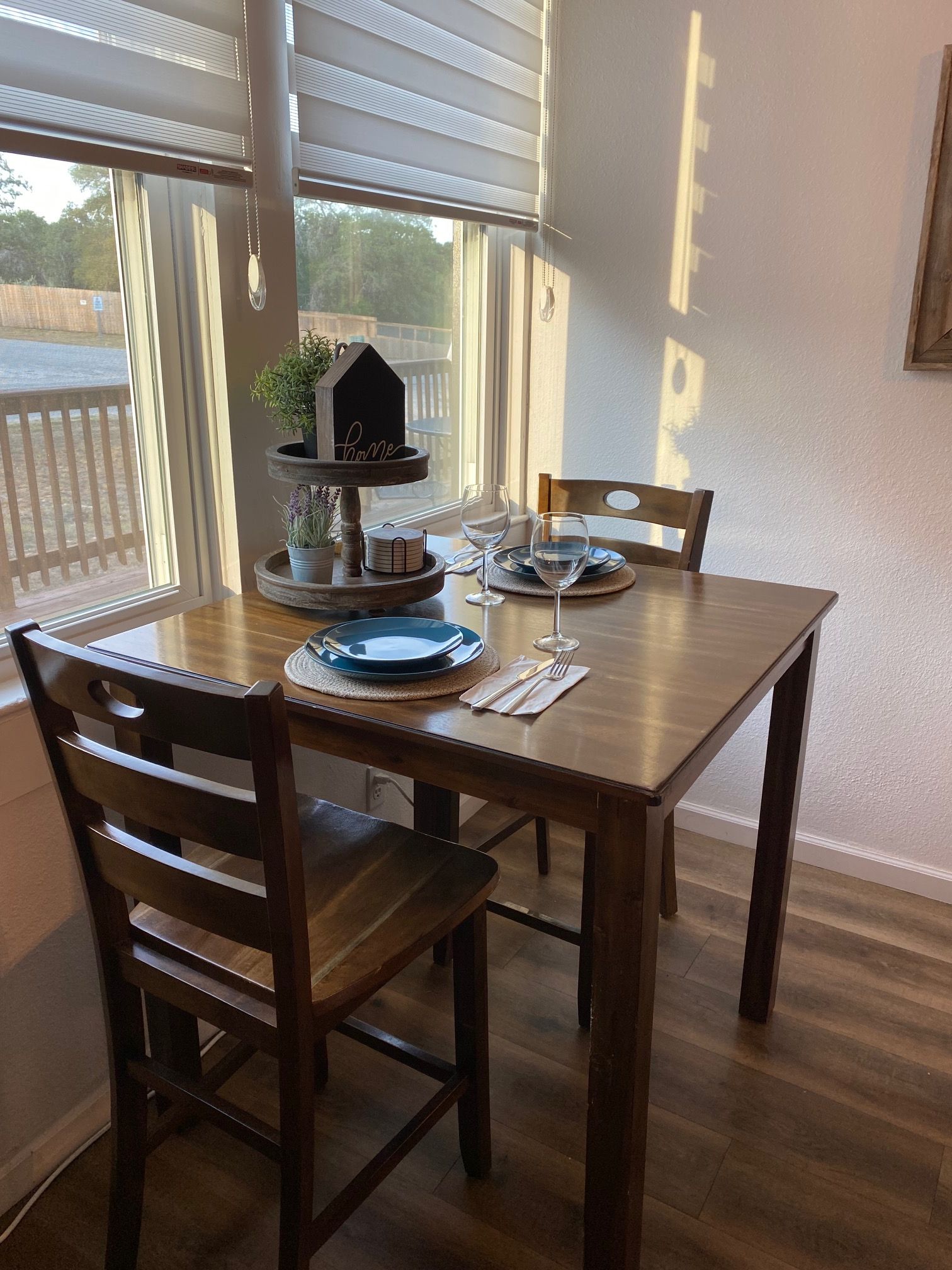 A dining table set with plates, glasses, and a small house-shaped decoration.