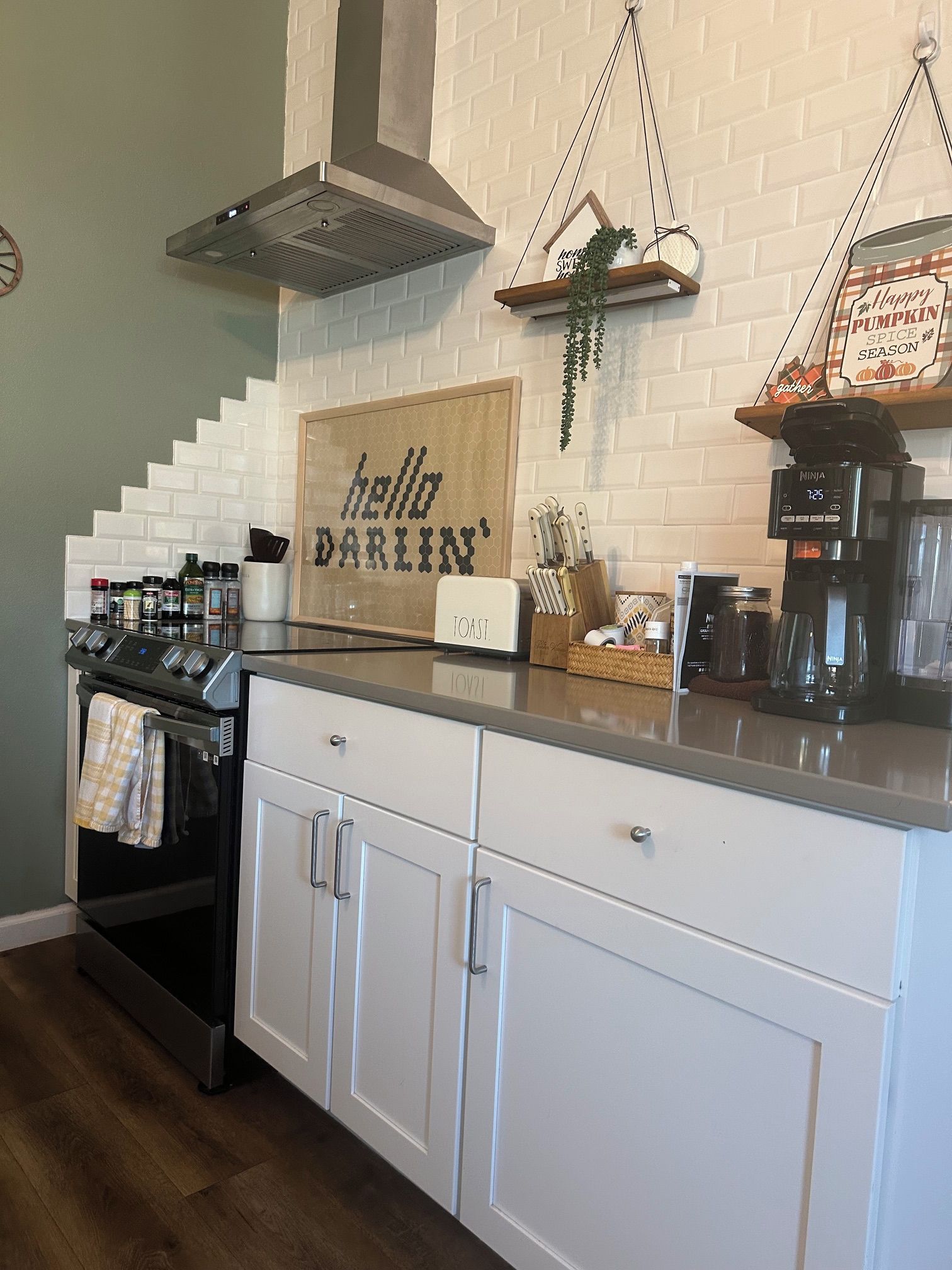 A kitchen with a white countertop, a stove, cabinets, and a hanging sign that reads 'hello DARLIN''.