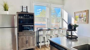 A modern kitchen with a built-in oven, a dining area with white chairs, and a large window providing a view of the outdoors. - Three bedroom house near Main St. in Bandera, TX (Bandera)