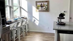 A modern kitchen with a dining area, large windows, and a painting on the wall. - Three bedroom house near Main St. in Bandera, TX (Bandera)
