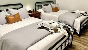 A room with two beds, each with white bedding and brown pillows. There is a framed picture on the wall above the beds. - Three bedroom house near Main St. in Bandera, TX (Bandera)