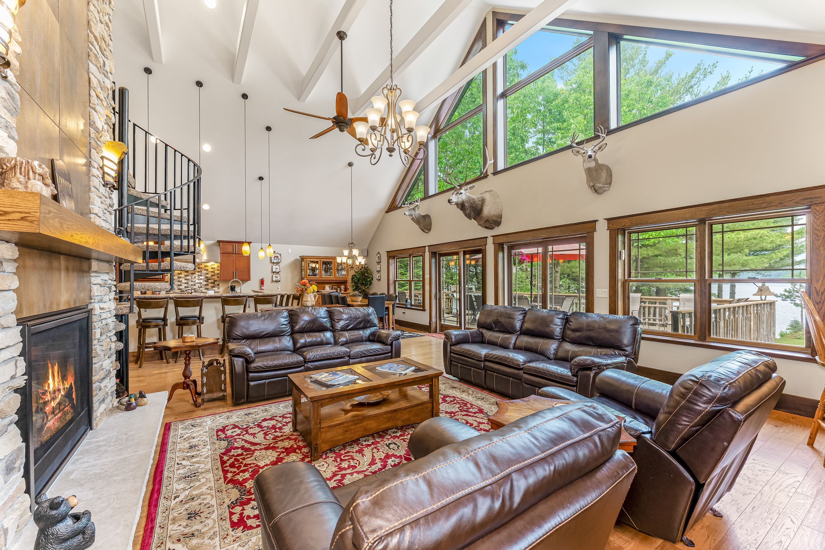 A spacious living room with leather sofas, a fireplace, and large windows overlooking a deck.