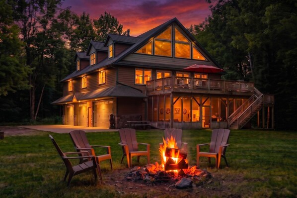 A large house with a deck, a fire pit, and outdoor seating.