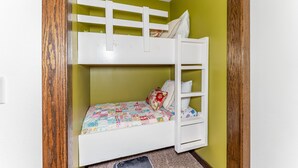 A bunk bed with a quilted bedspread, a pillow, and a ladder.