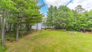 A grassy outdoor area with trees and a wooden deck.