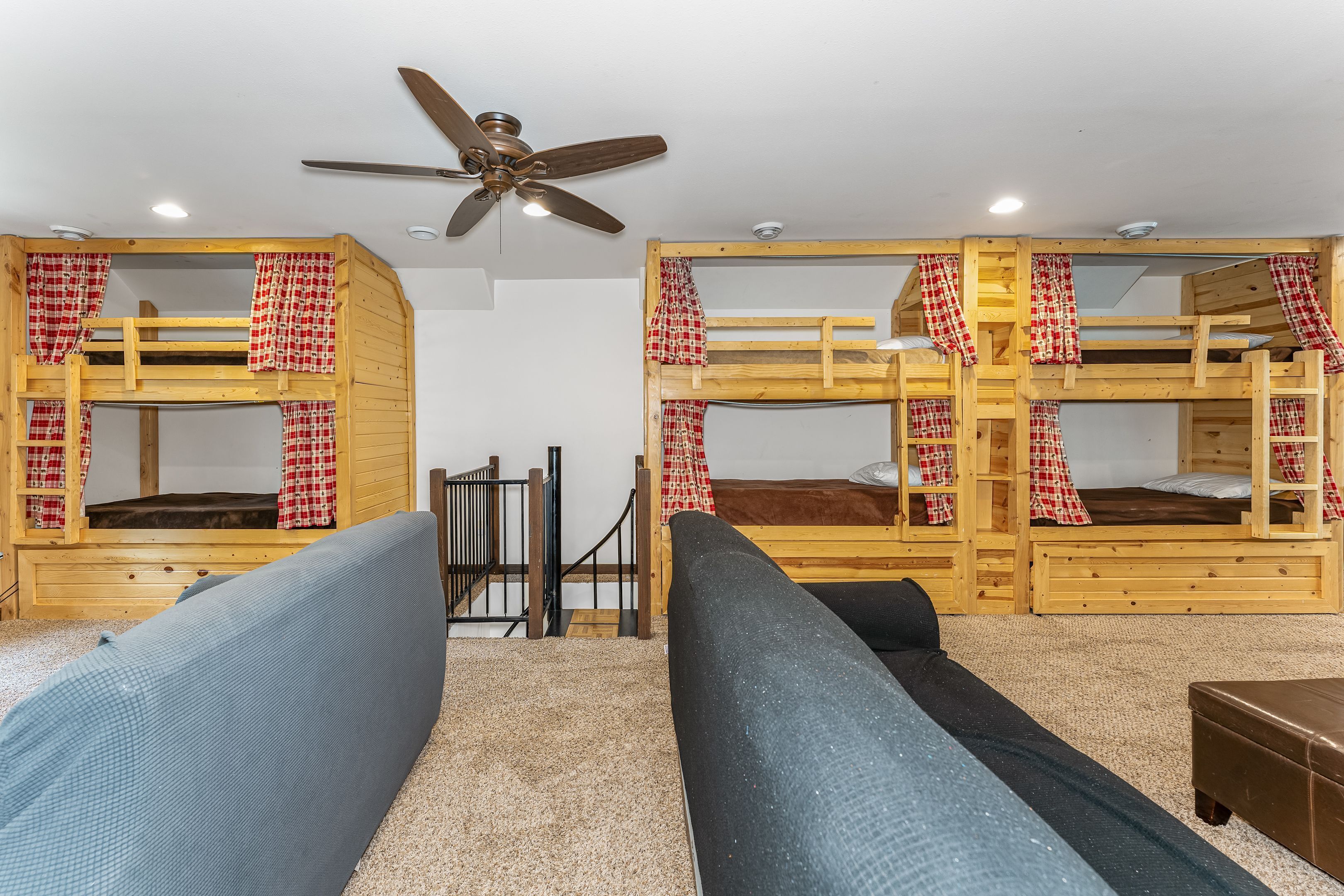 A room with bunk beds, a ceiling fan, and a sofa.
