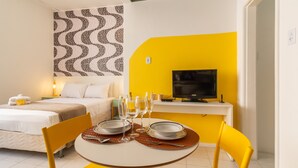 A compact hotel room with a bed, a dining table set with plates and glasses, a television, and a patterned wall. - Cozy 6 Minutes From Copacabana Beach Br710 (Rio de Janeiro)