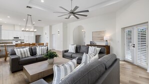 Un salon moderne avec des canapés gris, une table basse en bois et un ventilateur de plafond.