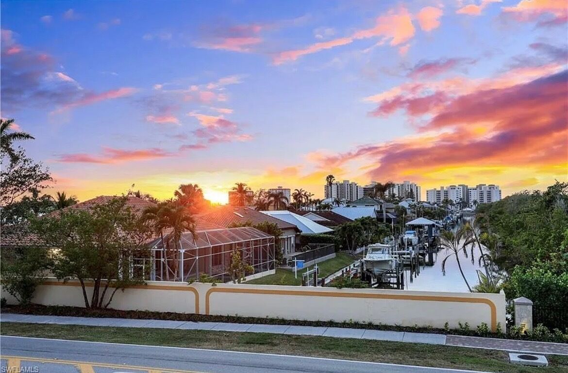 Un quartier résidentiel avec un port de plaisance, des maisons et un ciel au coucher du soleil.