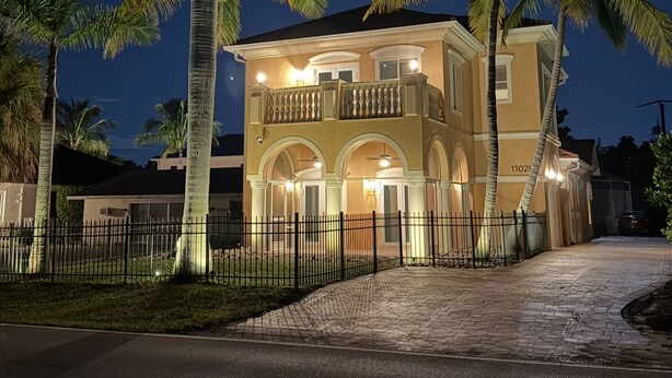 Une maison à deux étages dotée d’un balcon, de fenêtres en arc de cercle et d’une allée pavée.