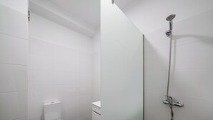A modern bathroom with white tiles, a toilet, and a shower with a handheld showerhead. - Golden Star AV – Modern Retreat in Funchal (Funchal)