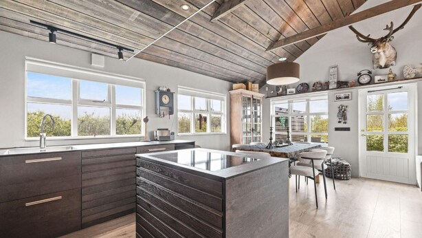 Une cuisine moderne avec un îlot central, des armoires en bois et un plafond au style rustique.