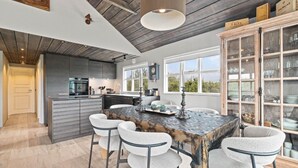 A modern kitchen with a central island, bar stools, and a wooden cabinet with glass doors. - Beautiful cottage in a great location. Golden circle (Bláskógabyggð)