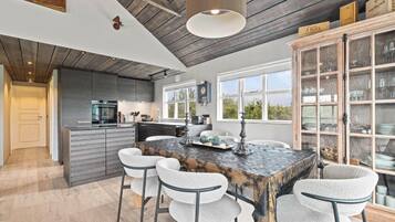 A modern kitchen with a central island, bar stools, and a large cabinet with glass doors.