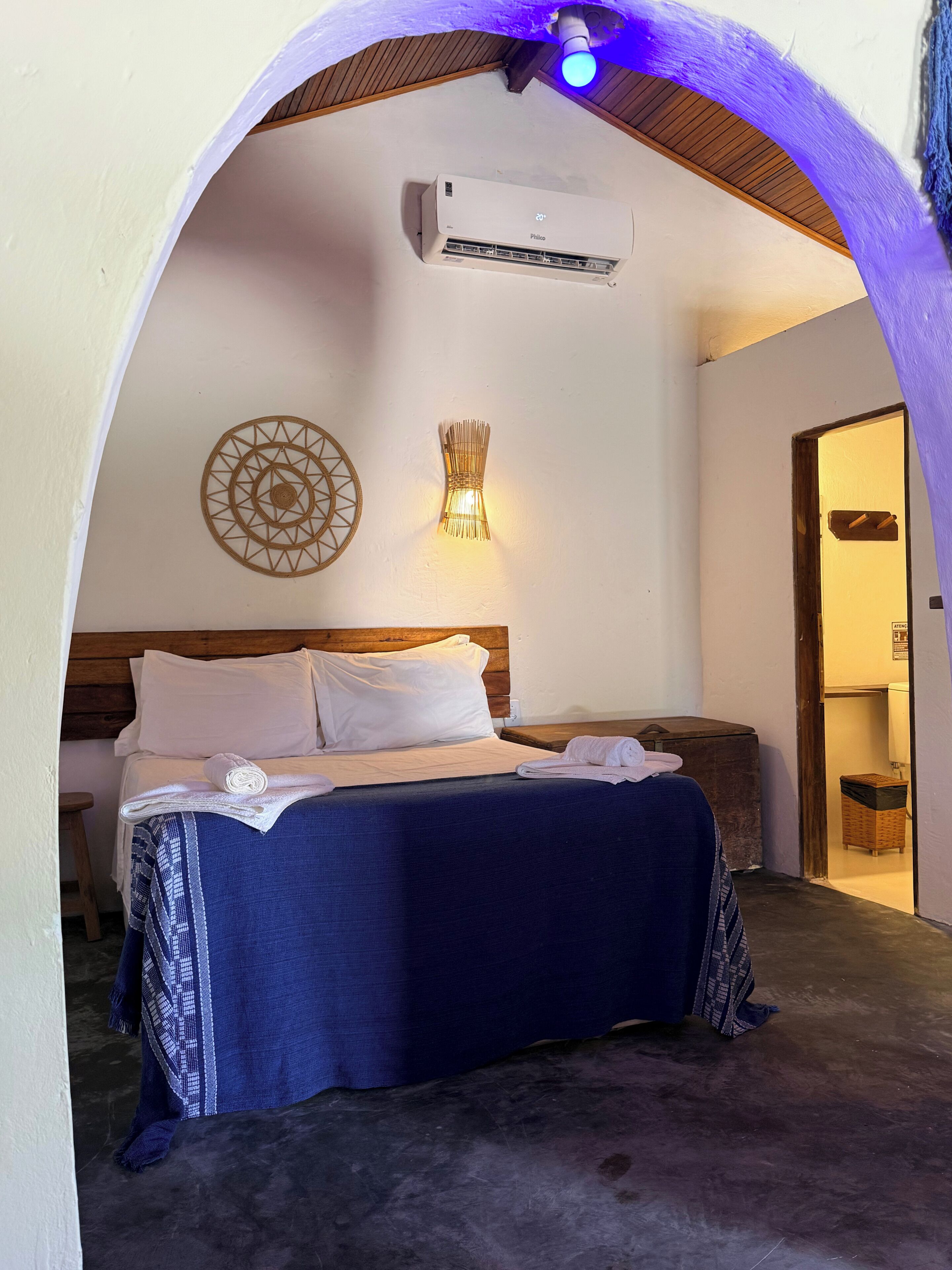 Ein Schlafzimmer mit Bett, Wand-Klimaanlage, dekorativer Wandleuchte und Holzboden.