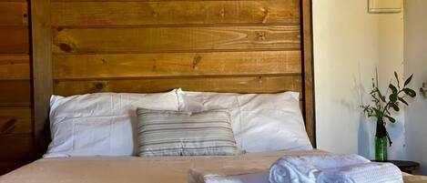 A bed with a wooden headboard, white bedding, and a folded towel.